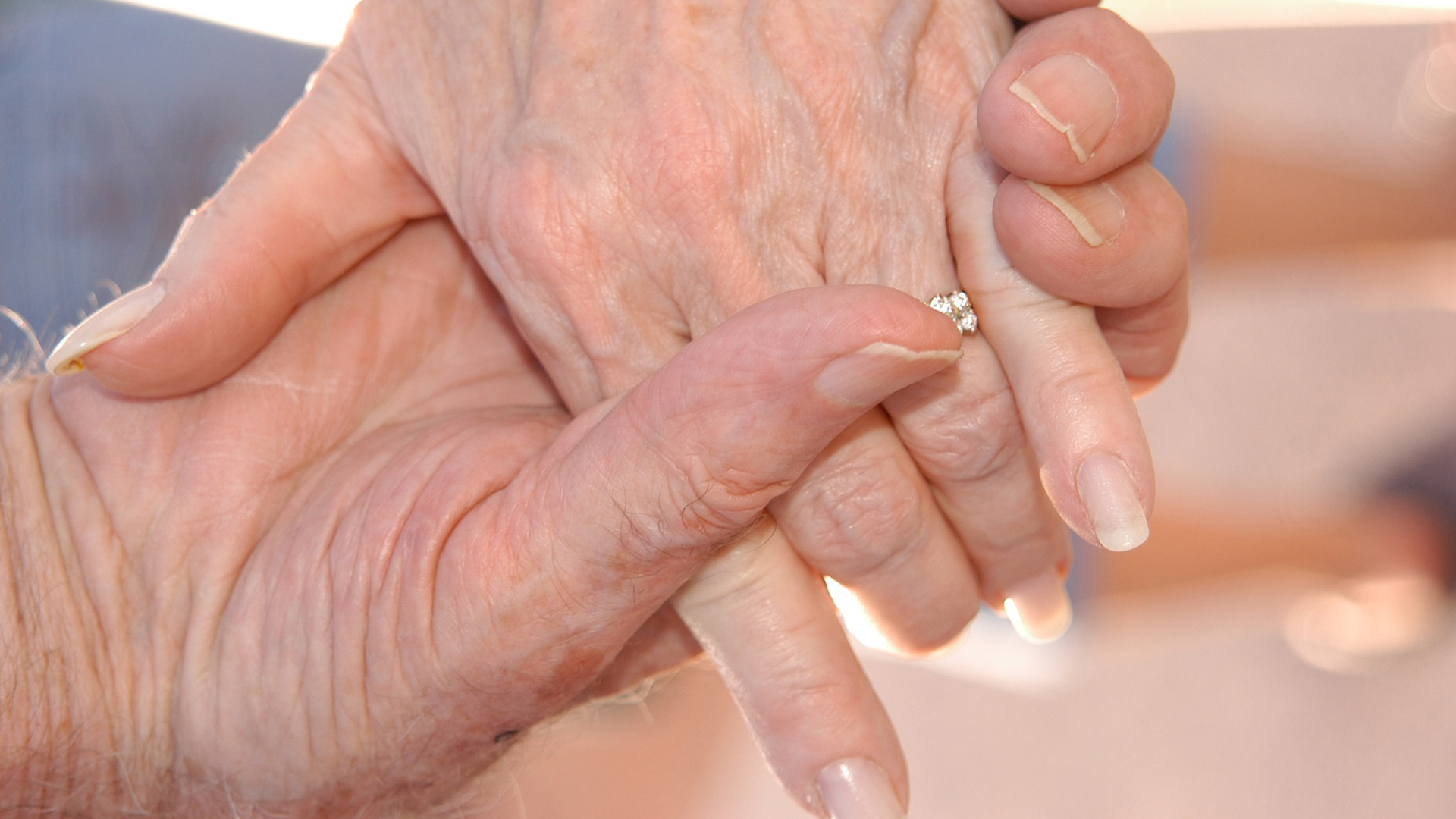 Äldre par som håller varandra i händerna - närbild på händerna