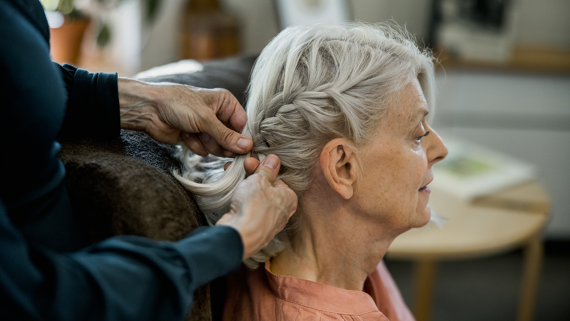 Äldre kvinna får sitt hår flätat