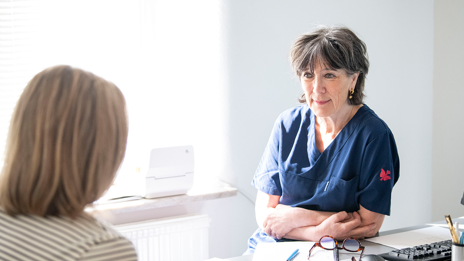 Läkare har samtal med patient vid skrivbord